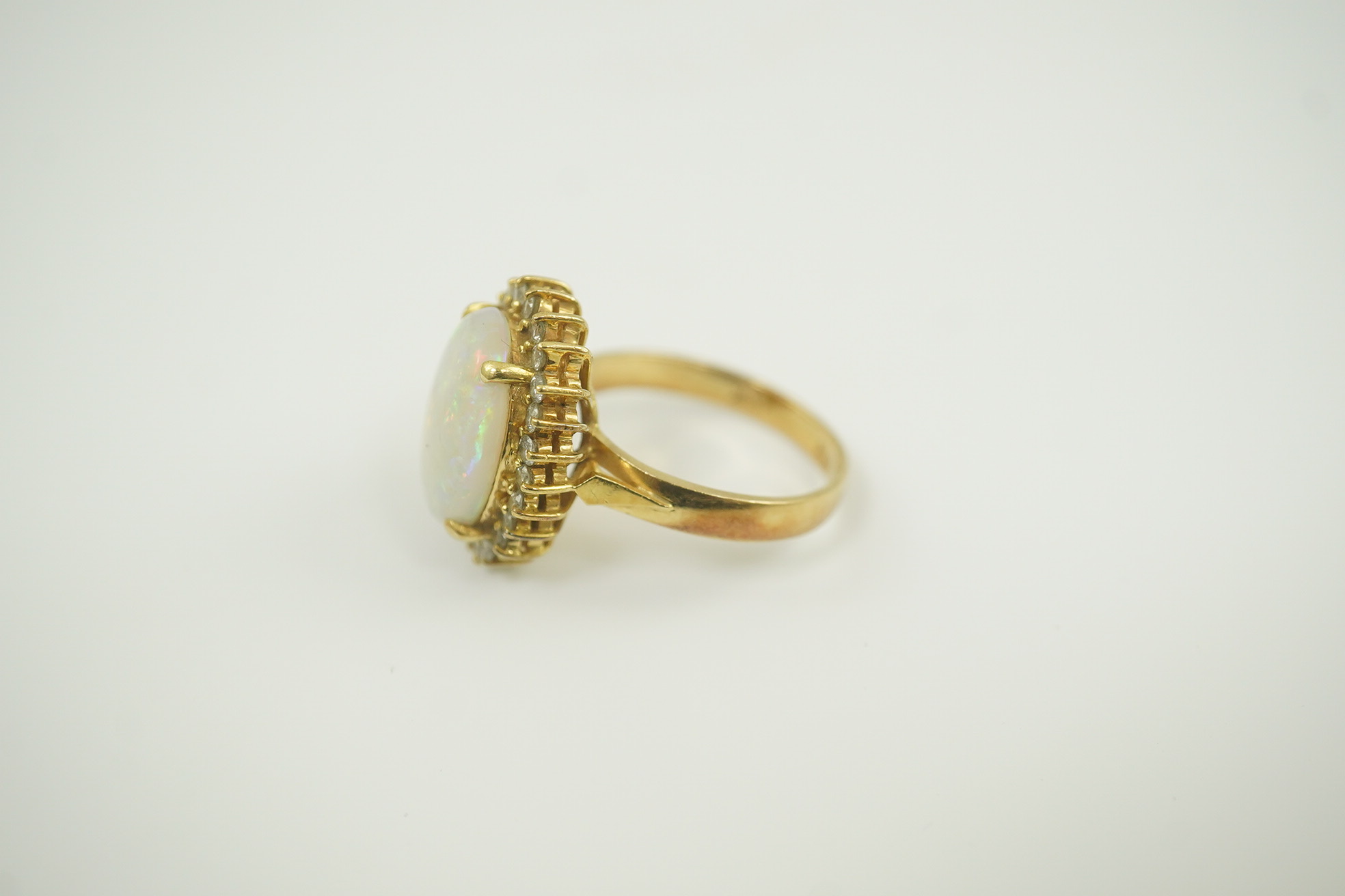 An 18k gold, white opal and diamond set oval cluster ring